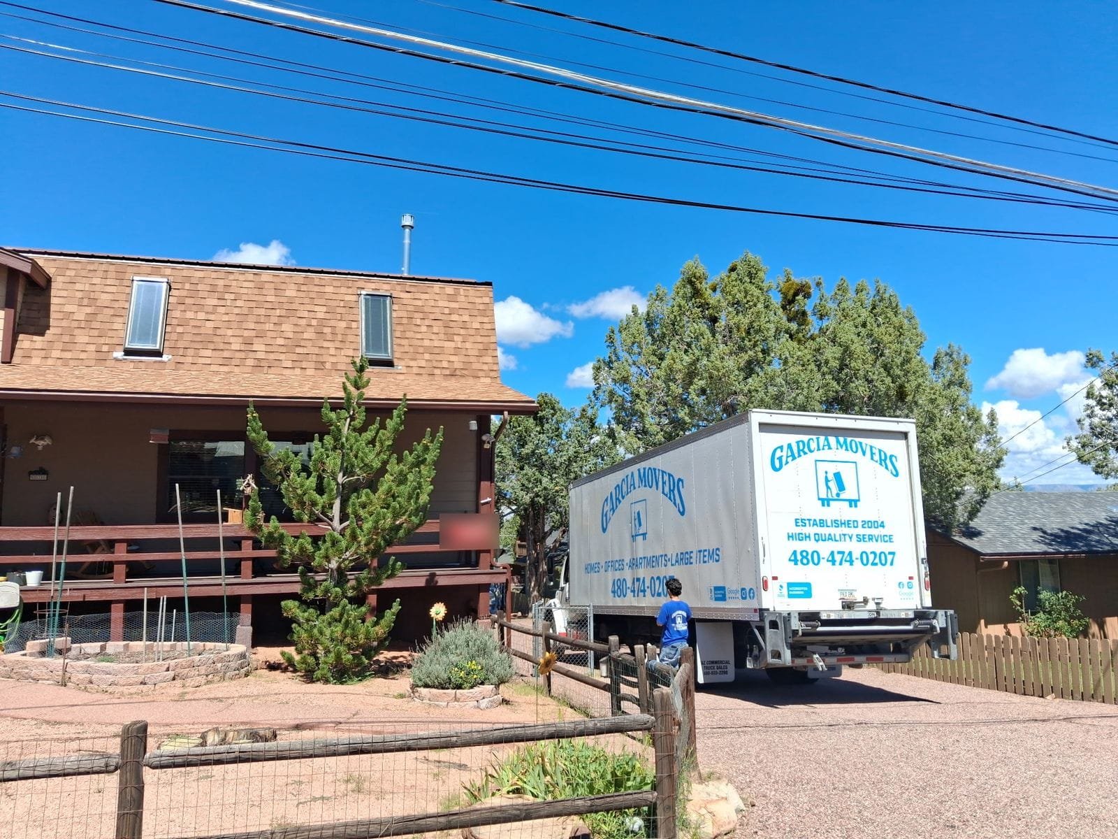 A Garcia mover at the back of the truck outside a home with a wooden deck